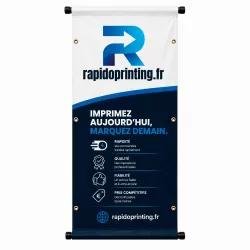 Bâche publicitaire personnalisée sur fond bleu avec logo rapideprinting.fr et texte "Imprimez aujourd'hui, marquez demain" affichés verticalement.