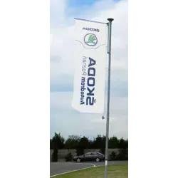 Drapeau publicitaire sur pied extérieur avec logo et texte sur fond ciel, installé sur mât en plage.