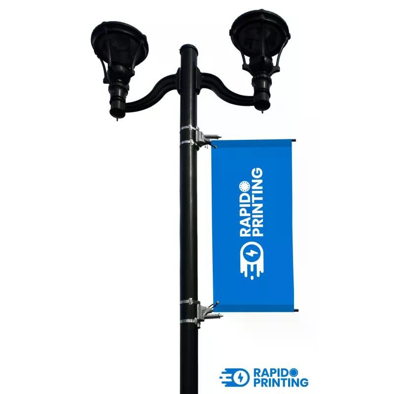 Support kakémono pour candélabres fixé sur lampadaire, banderole bleue imprimée Rapid Printing, cadre et fixations visibles.